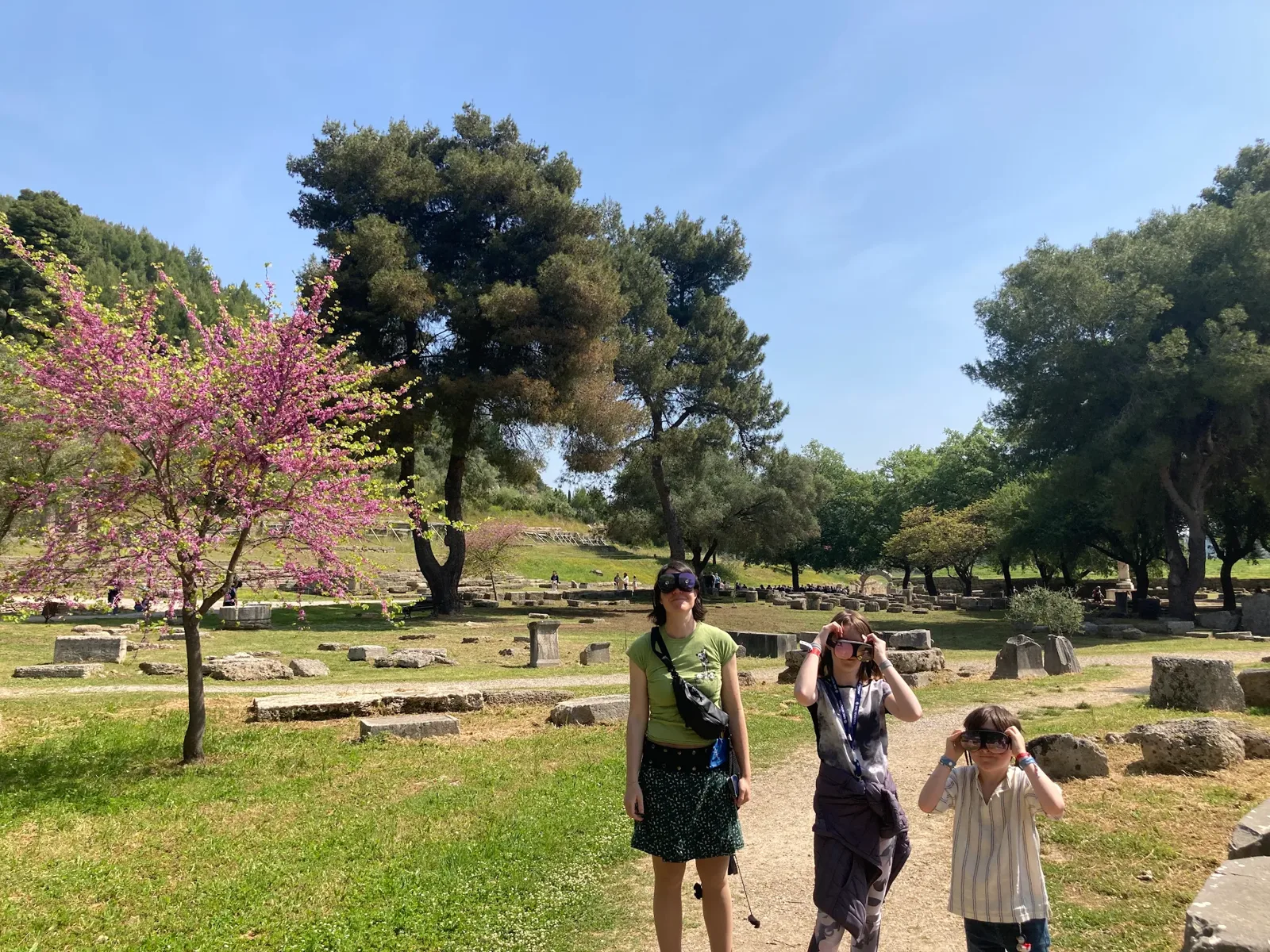 A family exploring Ancient Olympia with VR glasses on a sunny day
