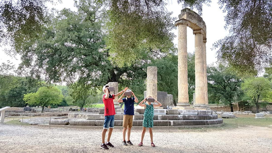 Family with kids visiting selfguided the Archaeological Site of Olympia with virtual reality glasses and audioguide 