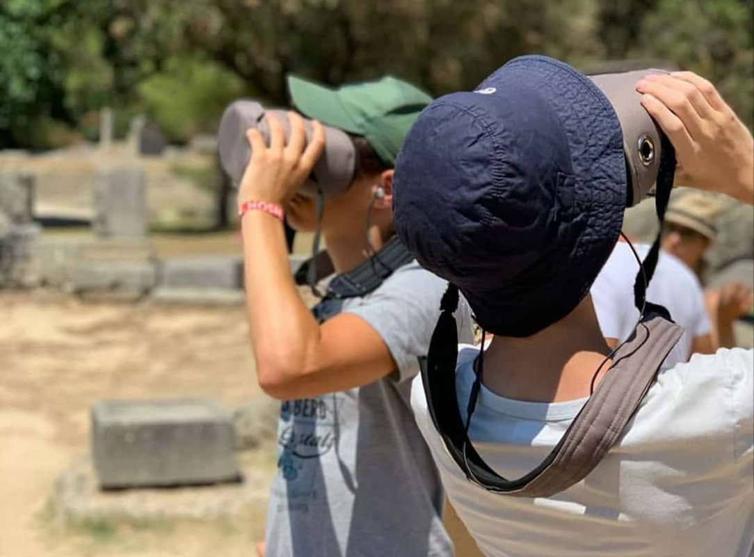 Visitors of Olympia Greece are using virtual reality glasses and an Audio Guide in a self guided tour of The Archaeological Site.